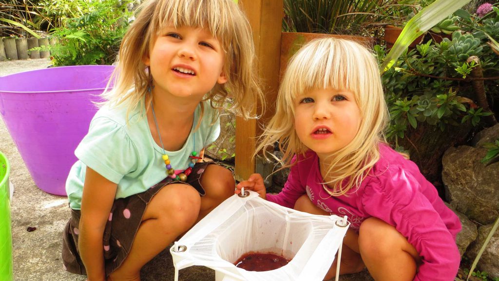 Two girls making juice from grapes