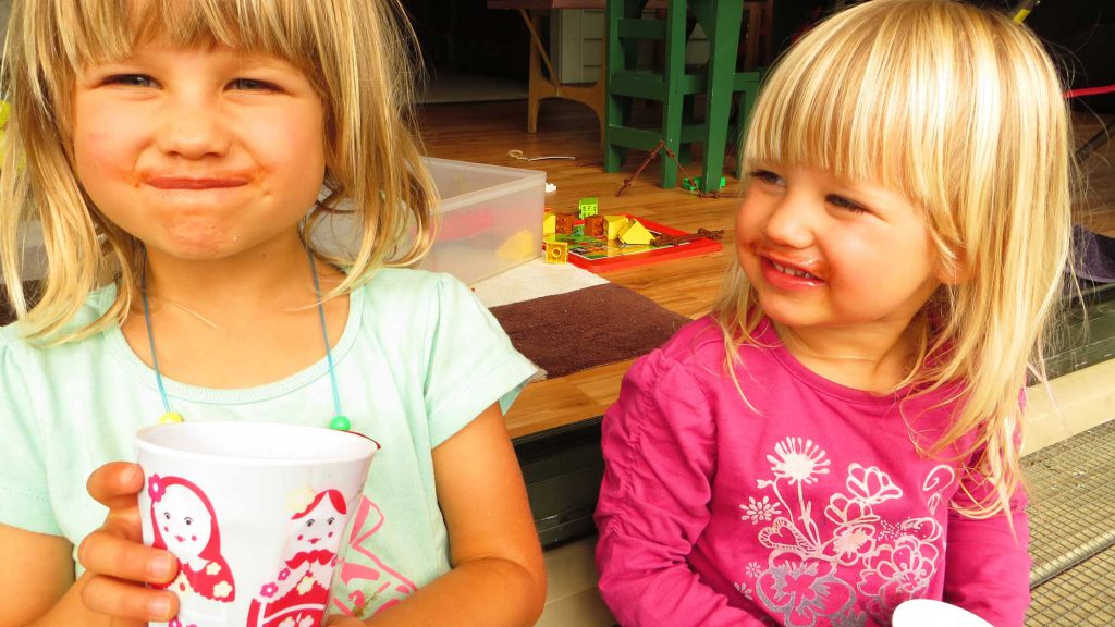 Two girls drinking juice from grapes